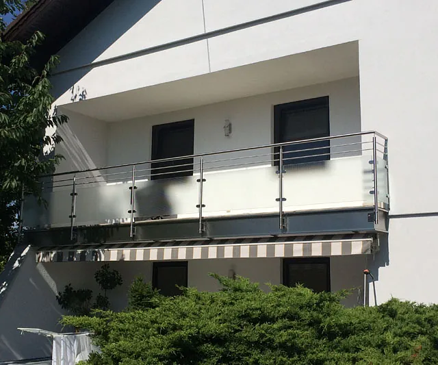 Ein weißes Gebäude mit einem stilvollen Balkon im oberen Bereich.