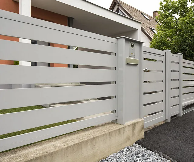 Ein weißer Zaun mit einem Tor vor einem Haus.