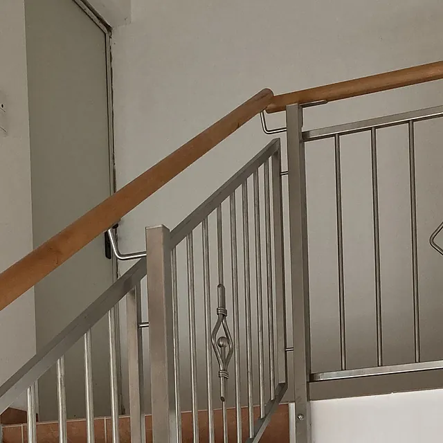 Eine Treppe, die ein Metallgeländer und einen handgefertigten Holzhandlauf aufweist.