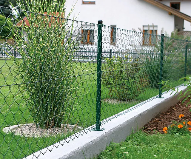 Ein Kettenzaun steht vor einem Haus und umschließt den Gartenbereich.