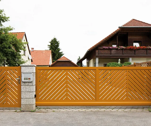 Ein großes Holztor mit einem gelben Zaun im Hintergrund.