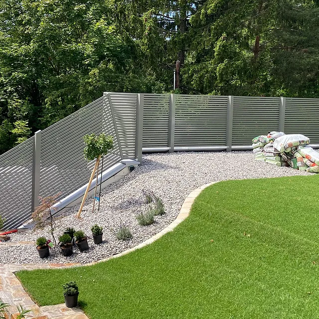 Ein Zaun steht vor einem Haus, umgeben von einem gepflegten Rasen.