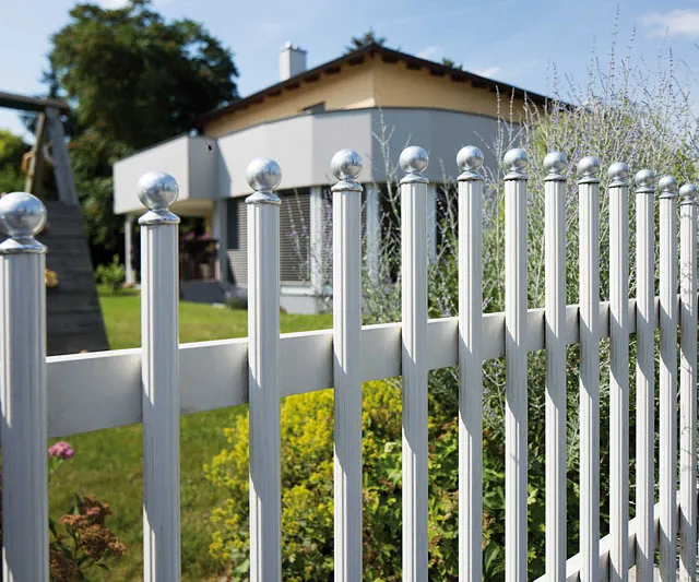 Ein Zaun in Weiß, der mit runden Metallkugeln geschmückt ist.