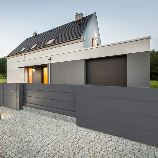 Zeitgenössisches Gebäude mit grauer Fassade und schwarzem Zaun.