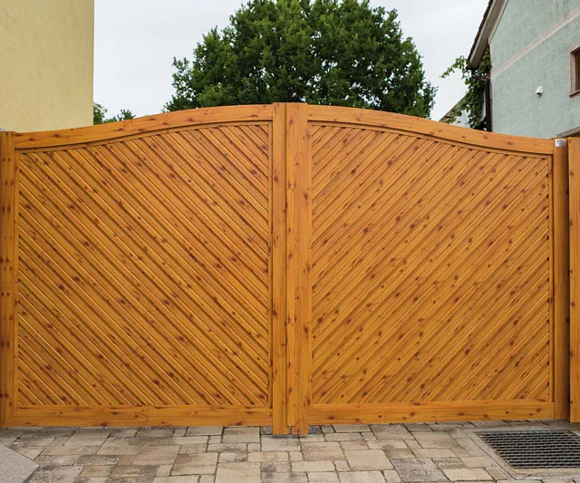 Ein rustikales Holztor steht vor einem Wohnhaus und trennt den Garten vom Gehweg.