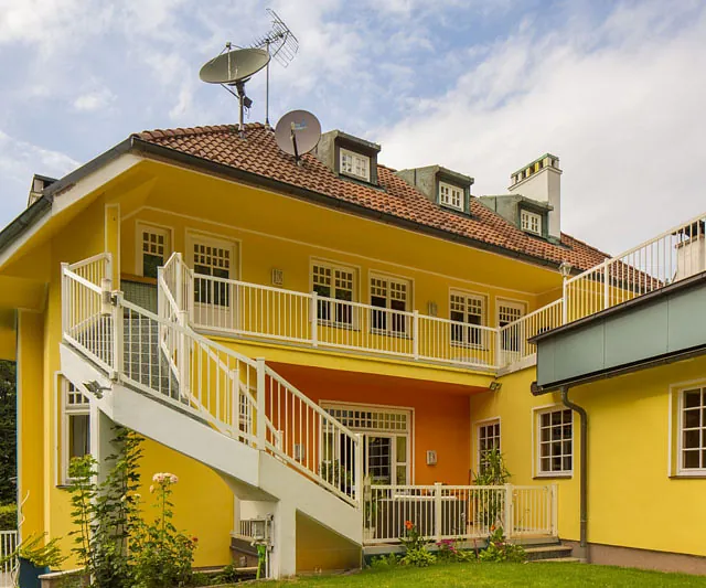 Ein gelbes Haus mit einem weißen Geländer.