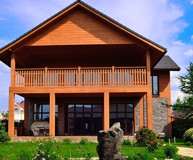 Eine Holzbank befindet sich vor einem Wohnhaus, umgeben von Blumen.