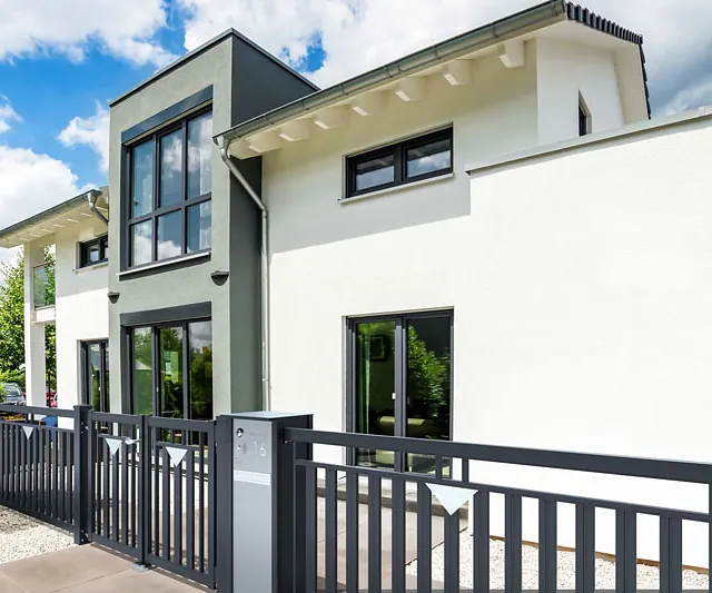 Stilvolles modernes Haus, das von einem Zaun und einem Tor umgeben ist.