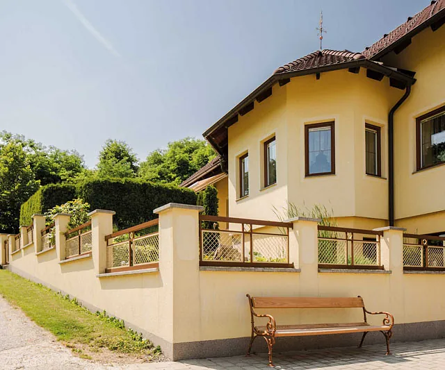 Eine Bank steht vor einem Haus, umgeben von einem gepflegten Garten.