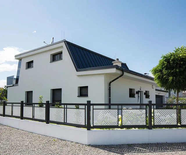  Ein Haus mit einem Zaun und einer strahlend roten Tür im Vordergrund.