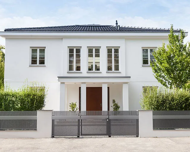 Ein weißes Haus mit einem Zaun und einem Tor im Vordergrund.