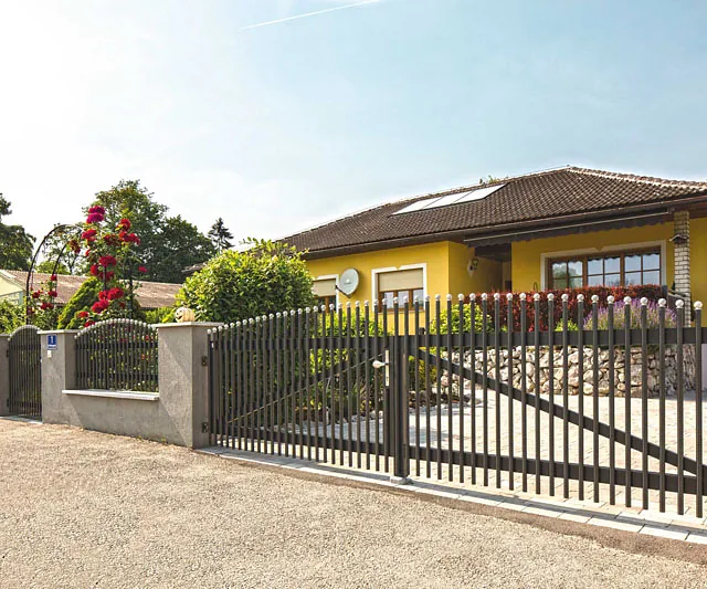 Ein Zaun mit einem Tor vor einem Haus.