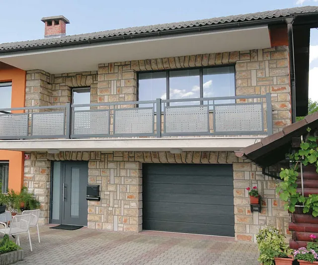 Ein Einfamilienhaus mit einem Zaun und einer markanten roten Eingangstür.