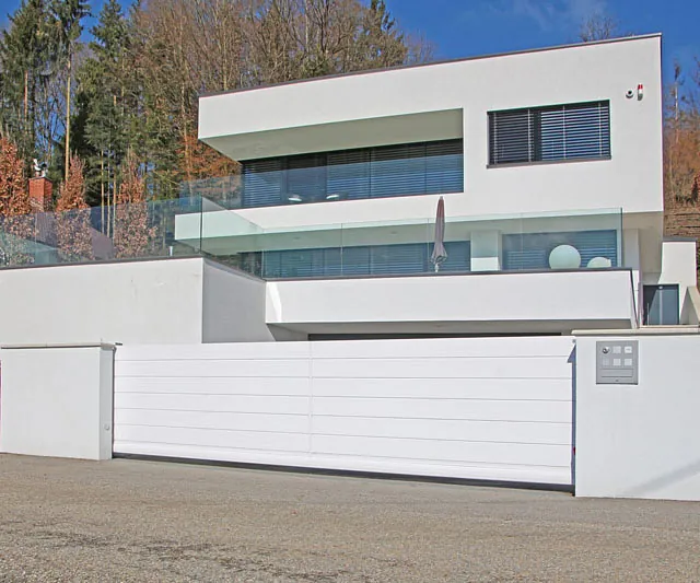 Elegantes weißes Haus, das durch ein großes Tor betreten wird.