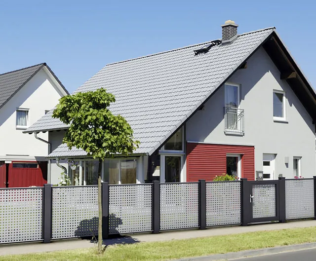 Ein Haus mit einem Zaun und einer roten Tür.