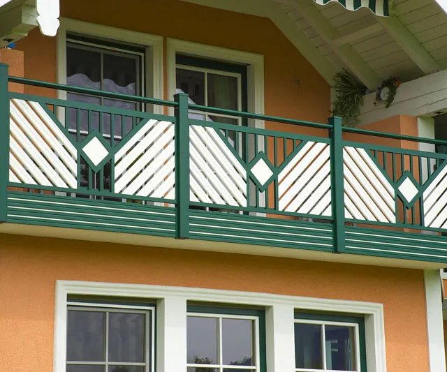 Ein orangefarbenes Haus steht im Vordergrund, umgeben von grünem Gras und einem blauen Himmel.