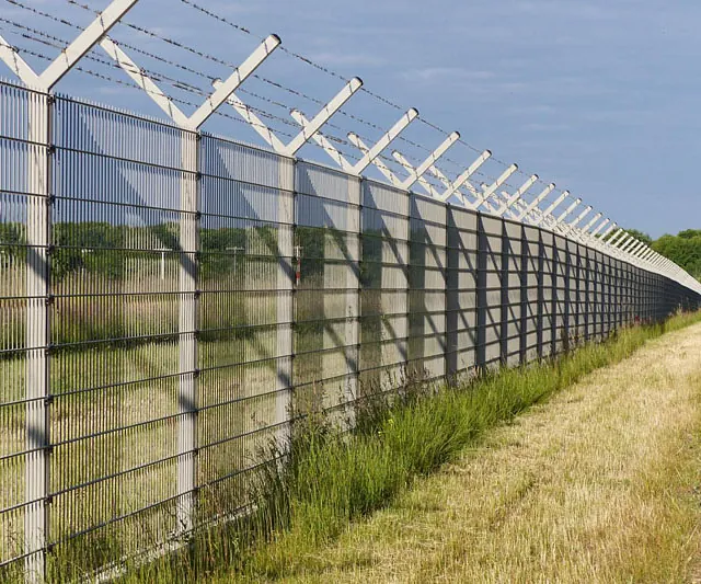  Ein Zaun mit Stacheldraht an der Seite einer Straße.
