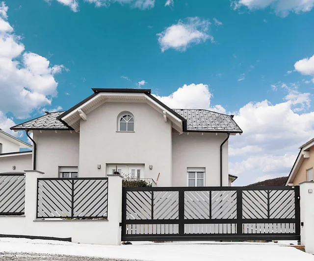 Ein weißes Haus mit einem Zaun umgeben, der das Grundstück abgrenzt.