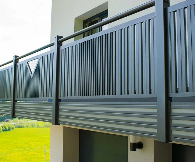 Ein Balkon mit einem Metallgeländer und einem grünen Rasen im Hintergrund.