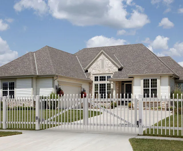 Ein weißer Lattenzaun steht vor einem Haus.
