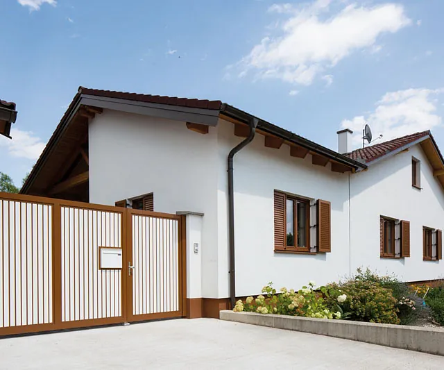 Ein Haus mit einem Holztor und einem weißen Zaun umgibt die Vorderansicht des Gebäudes.