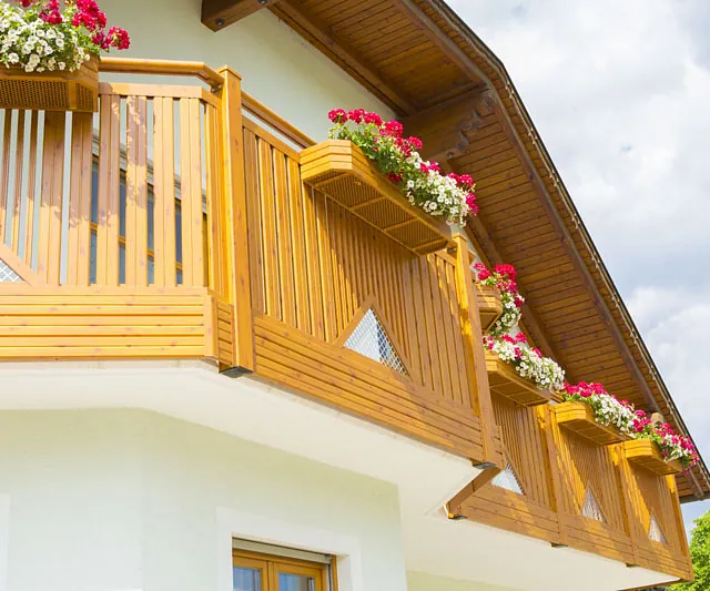Ein Holzbalkon mit bunten Blumen, der eine einladende Atmosphäre schafft.