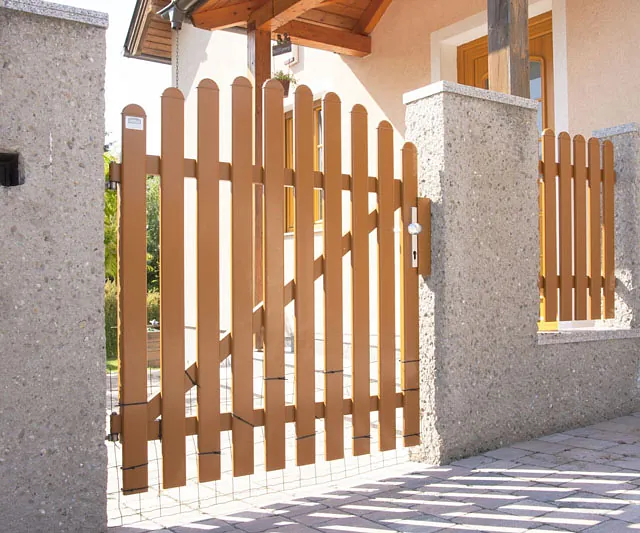 Ein Holzzaun mit einem Tor vor einem Haus.