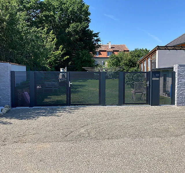 Eine Einfahrt, die von einem Tor und einem Zaun umgeben ist, bietet Sicherheit und Privatsphäre.