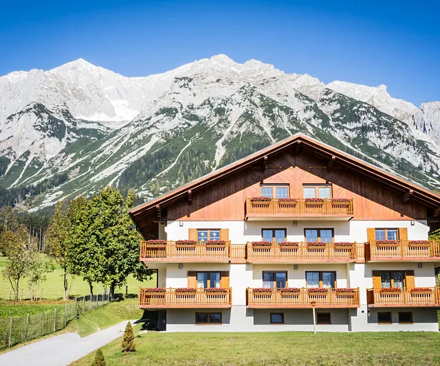 Vor einem Haus ist eine Bank platziert, ideal zum Entspannen im Freien.