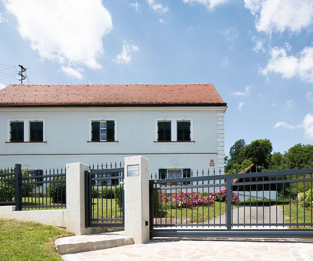 Weißes Haus, umgeben von einem eleganten schwarzen Eisenzaun.