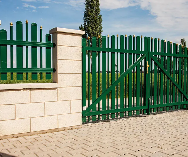 Eine grüne Tür mit einem weißen Zaun im Hintergrund.