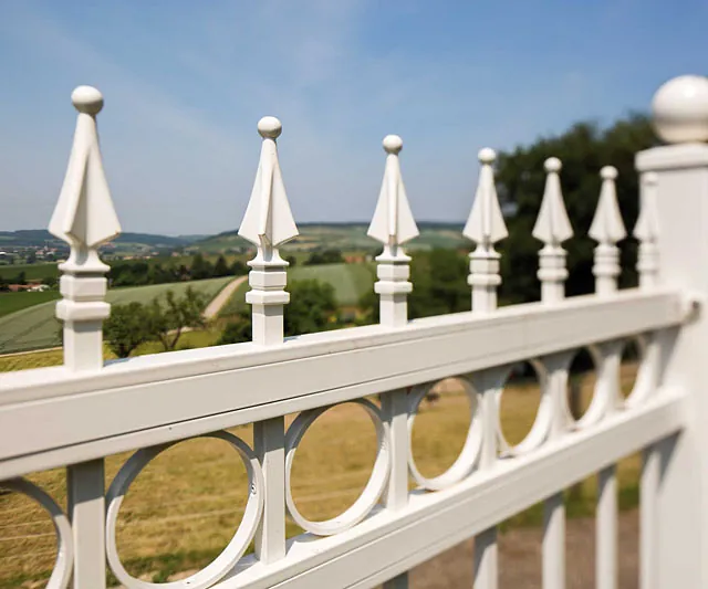 Ein weißer Zaun mit kunstvollen Geländern.